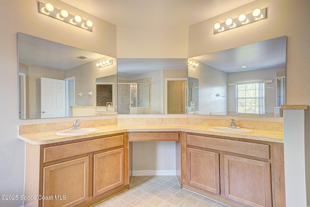 bathroom featuring a textured ceiling, double vanity, a sink, and a shower stall