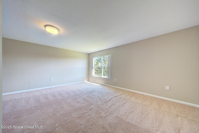 unfurnished room featuring a textured ceiling, carpet flooring, and baseboards