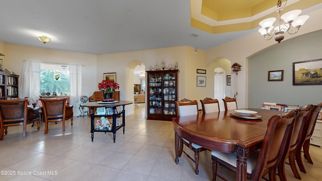 tiled dining space featuring a raised ceiling and an inviting chandelier