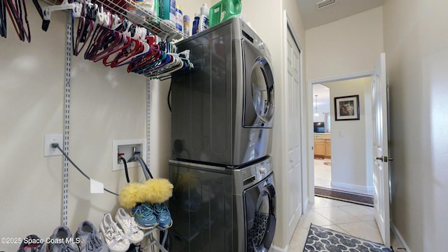 washroom featuring stacked washer / dryer and light tile patterned floors