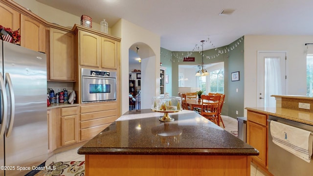 kitchen with pendant lighting, a kitchen island, light tile patterned floors, and appliances with stainless steel finishes