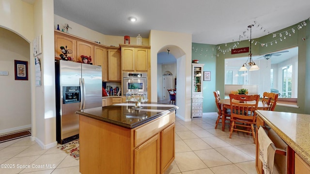 kitchen featuring a center island, stainless steel appliances, dark stone countertops, pendant lighting, and light tile patterned floors