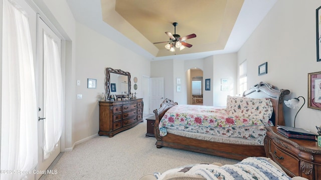 carpeted bedroom featuring ceiling fan and a raised ceiling