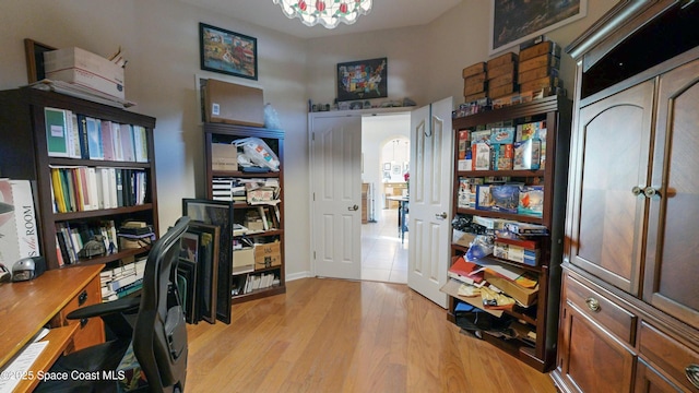 home office with a notable chandelier and light wood-type flooring