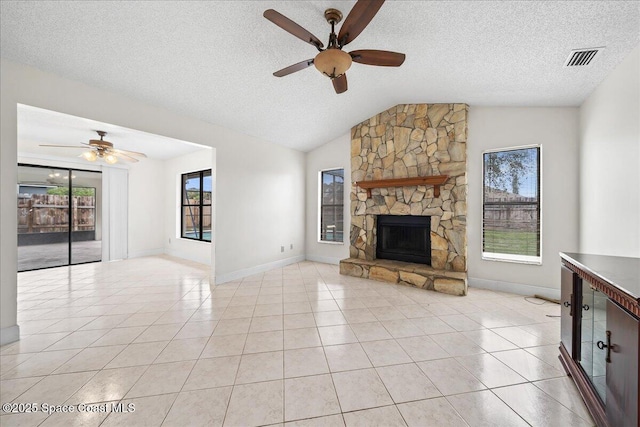 unfurnished living room with ceiling fan, light tile patterned flooring, a stone fireplace, and vaulted ceiling