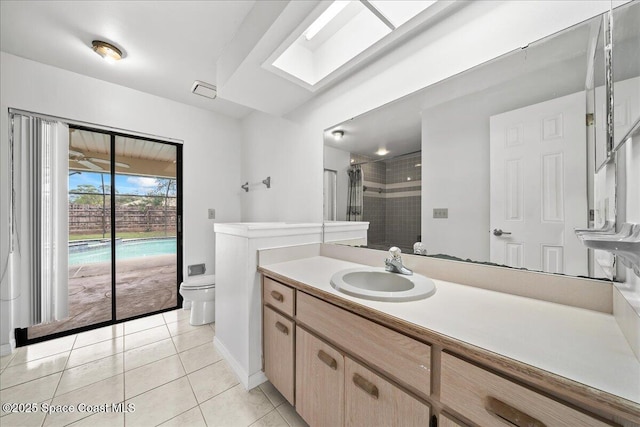 bathroom featuring vanity, tile patterned floors, a skylight, toilet, and a tile shower