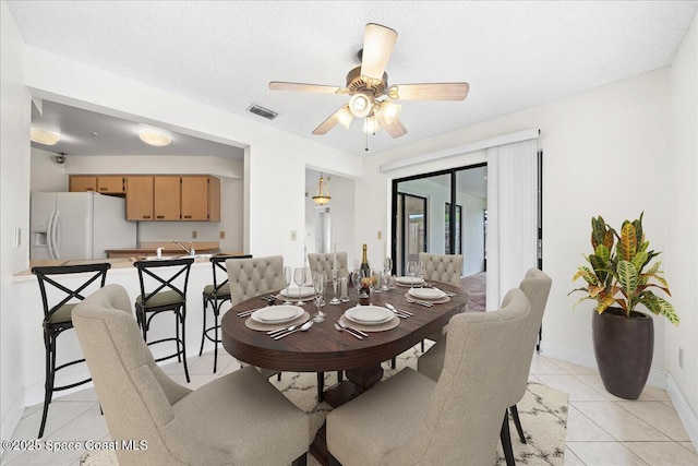 tiled dining space with ceiling fan, sink, and a textured ceiling