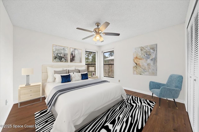 bedroom with ceiling fan, dark hardwood / wood-style floors, a closet, and a textured ceiling