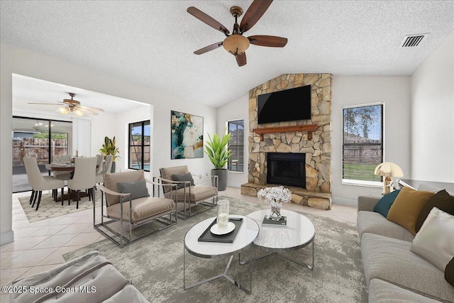 tiled living room with a fireplace, a textured ceiling, vaulted ceiling, and a healthy amount of sunlight