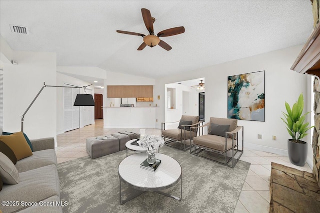 tiled living room featuring ceiling fan, lofted ceiling, and a textured ceiling
