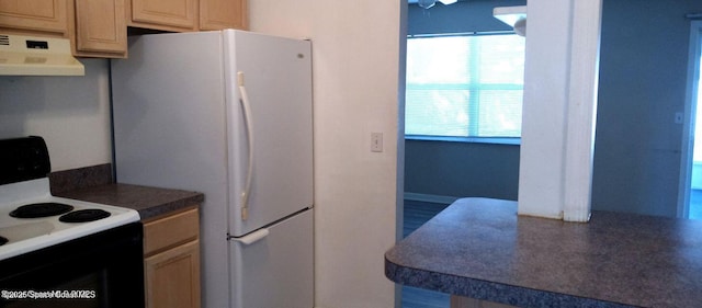 kitchen with black electric range, ventilation hood, freestanding refrigerator, light brown cabinetry, and dark countertops