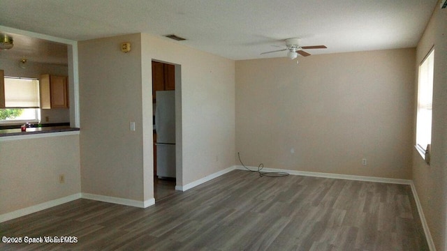 spare room with dark wood-style floors, visible vents, and baseboards