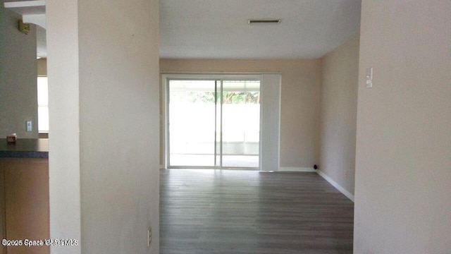 spare room with dark wood-style floors, visible vents, and baseboards