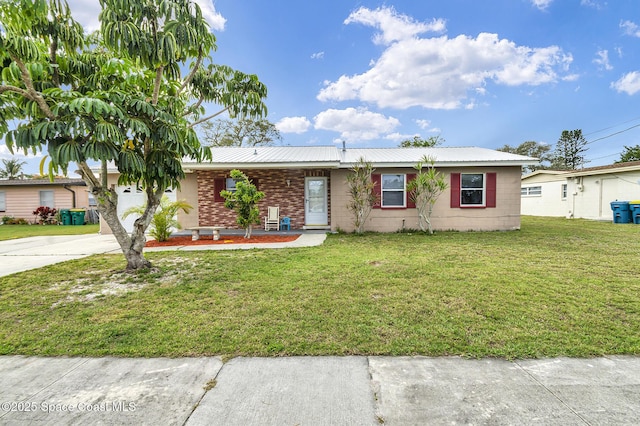 ranch-style home with metal roof, driveway, a front lawn, and concrete block siding