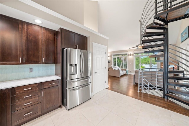 kitchen with light tile patterned floors, backsplash, stainless steel fridge, and dark brown cabinetry