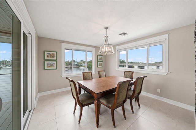 dining area with a notable chandelier, a water view, and light tile patterned flooring