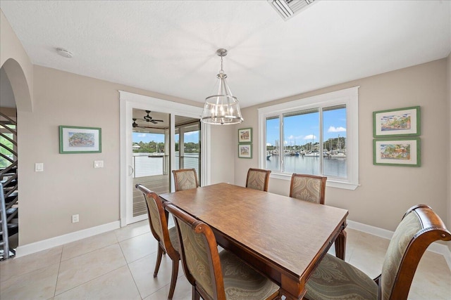 tiled dining area featuring a water view and an inviting chandelier