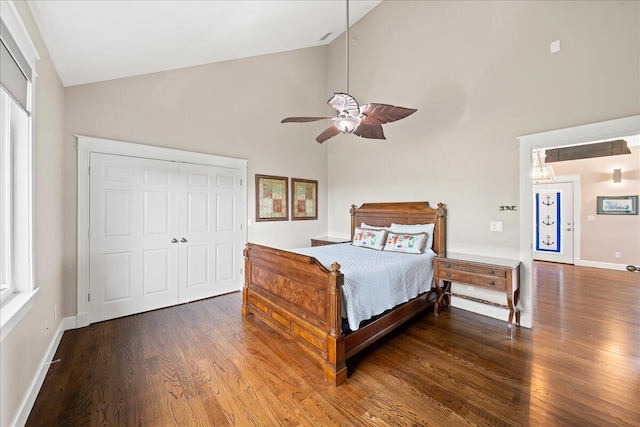 bedroom featuring a closet, high vaulted ceiling, dark hardwood / wood-style flooring, ceiling fan, and multiple windows