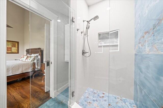 bathroom with hardwood / wood-style floors and a shower with shower door