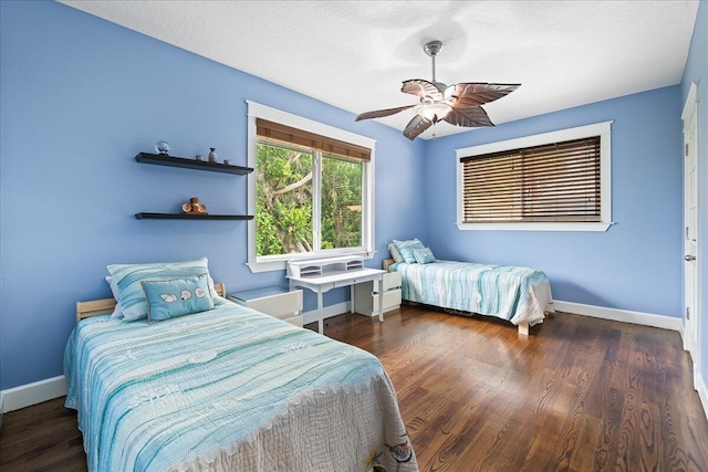 bedroom with ceiling fan, a textured ceiling, and dark hardwood / wood-style floors