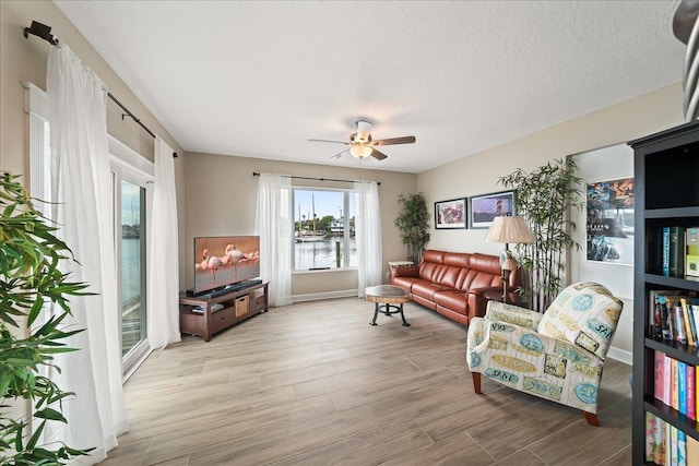 sitting room with light wood-type flooring, a textured ceiling, and ceiling fan