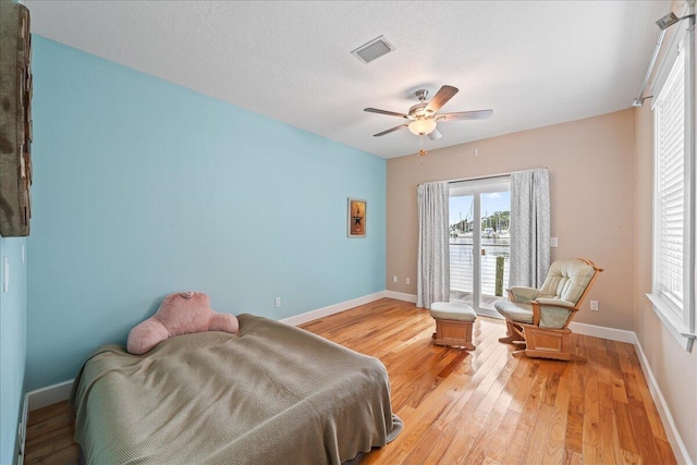 bedroom featuring ceiling fan, light hardwood / wood-style floors, and a textured ceiling