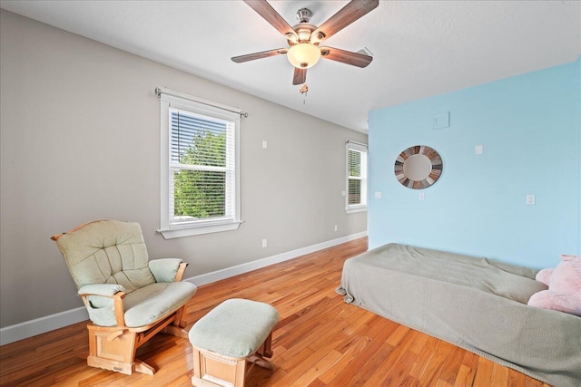 living area featuring light hardwood / wood-style floors and ceiling fan