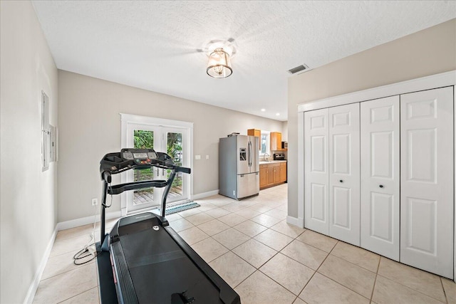 exercise area featuring sink, light tile patterned flooring, and a textured ceiling