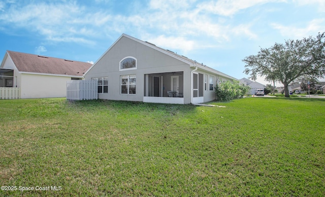 rear view of property featuring a lawn and a sunroom