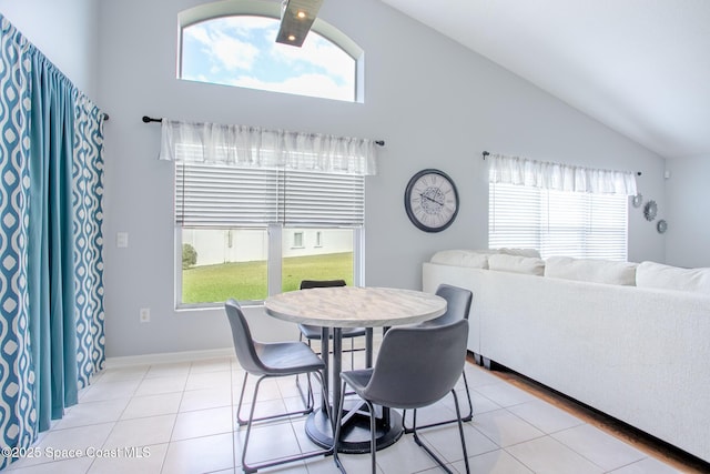 dining room with plenty of natural light, light tile patterned floors, and high vaulted ceiling