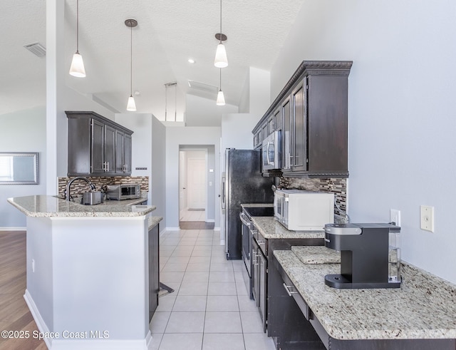 kitchen with decorative backsplash, dark brown cabinetry, stainless steel appliances, vaulted ceiling, and decorative light fixtures