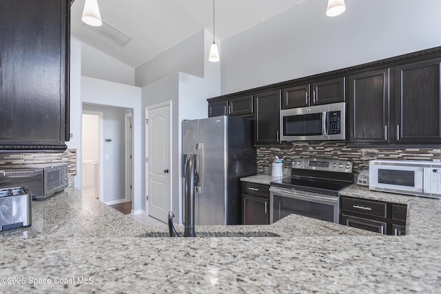 kitchen featuring decorative backsplash, light stone counters, stainless steel appliances, vaulted ceiling, and decorative light fixtures