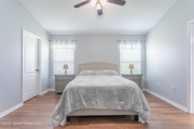 bedroom featuring multiple windows, wood-type flooring, and ceiling fan