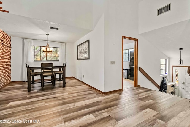 dining room with hardwood / wood-style floors, a notable chandelier, and lofted ceiling