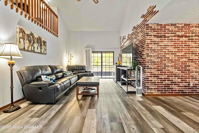 living room featuring hardwood / wood-style floors, a towering ceiling, and brick wall