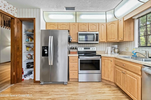 kitchen featuring light brown cabinetry, sink, stainless steel appliances, and light hardwood / wood-style flooring