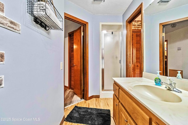 bathroom with a shower with door, vanity, and hardwood / wood-style floors