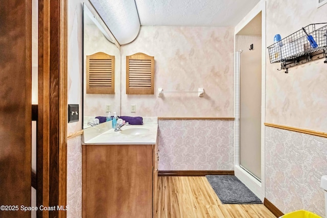 bathroom featuring a textured ceiling, vanity, wood-type flooring, and a shower with shower door