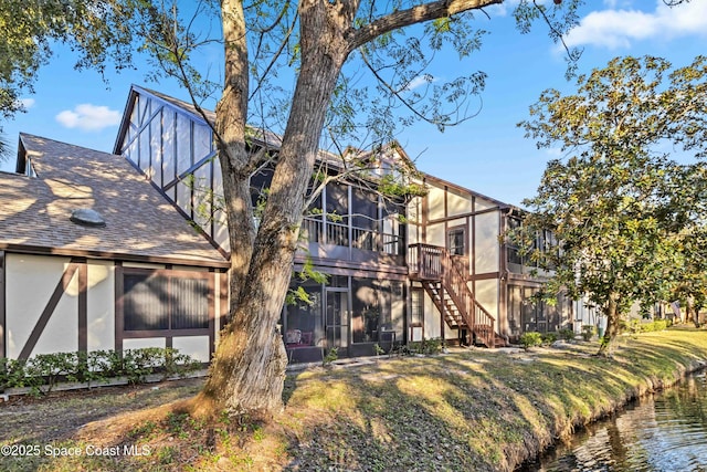 rear view of property featuring a sunroom and a water view