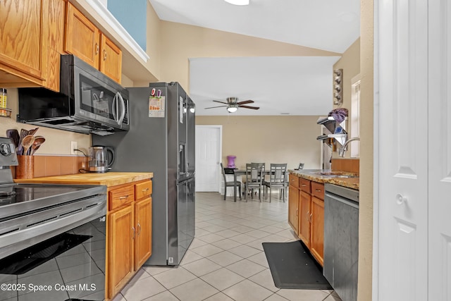 kitchen with ceiling fan, sink, stainless steel appliances, vaulted ceiling, and light tile patterned floors