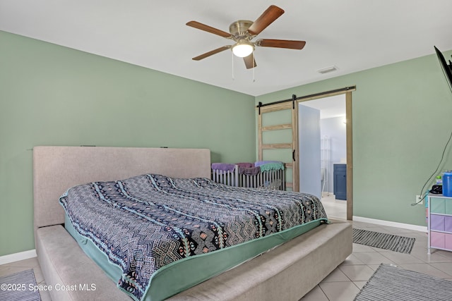 tiled bedroom featuring ceiling fan, a barn door, and connected bathroom