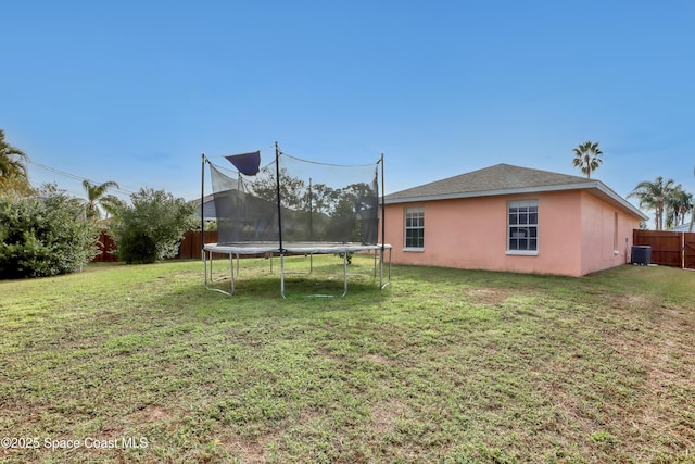 view of yard with a trampoline and central AC