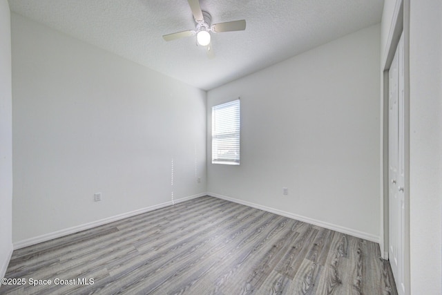 unfurnished bedroom with ceiling fan, a closet, light hardwood / wood-style floors, and a textured ceiling