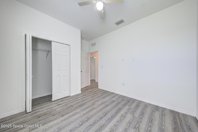 unfurnished bedroom featuring ceiling fan, a closet, light hardwood / wood-style floors, and a textured ceiling