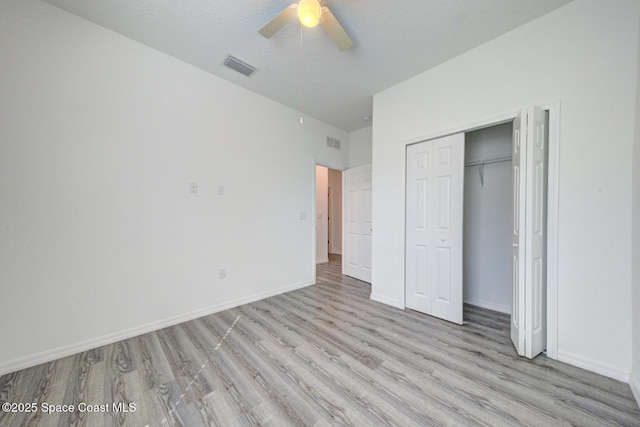 unfurnished bedroom with ceiling fan, a closet, a textured ceiling, and light wood-type flooring