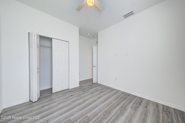 unfurnished bedroom featuring a textured ceiling, a closet, light hardwood / wood-style flooring, and ceiling fan