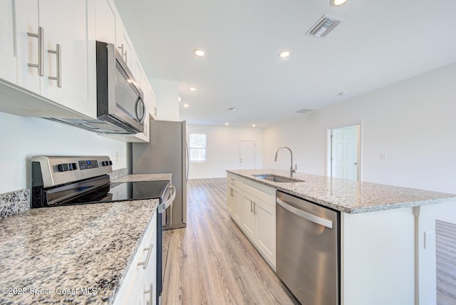 kitchen featuring a kitchen island with sink, white cabinets, sink, light stone counters, and stainless steel appliances