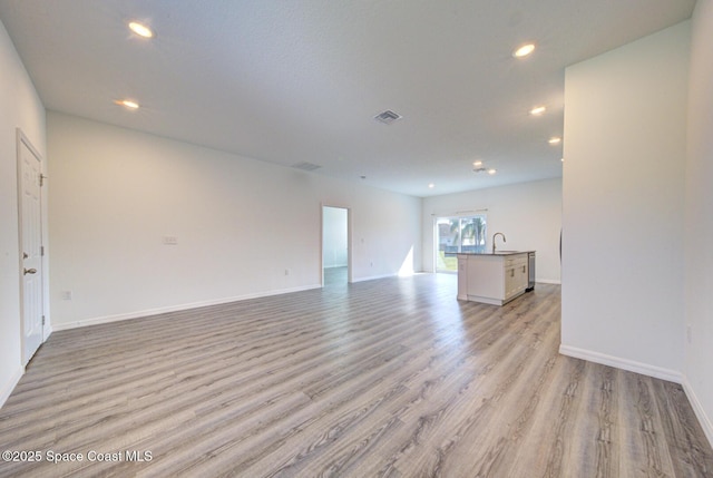 unfurnished living room featuring light hardwood / wood-style floors and sink