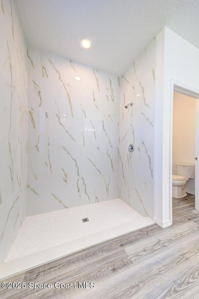 bathroom featuring hardwood / wood-style flooring, toilet, walk in shower, and a textured ceiling