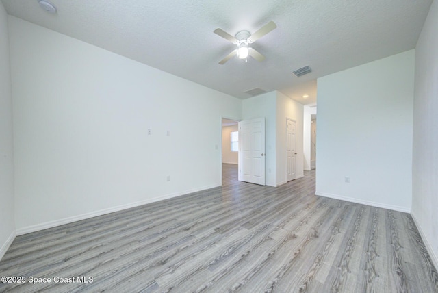 unfurnished room with ceiling fan, a textured ceiling, and light wood-type flooring